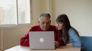 Nurse assisting an elderly man in learning to use a laptop at a nursing home, promoting digital literacy and support