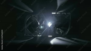 Against a black background, two cooling fans of a computer video card rotate in a backlight beam, creating moving shadows on a dark surface around. Macro. Closeup