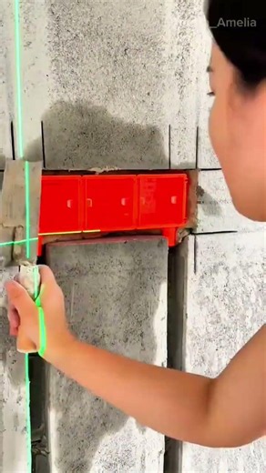 installing red electrical wall junction boxes into concrete wall with trowel and laser level line