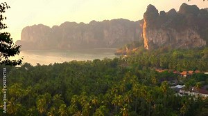 Tropical beach sunset with cliffs and palm trees. Ao Nang. Krabi Province, Thailand.