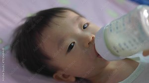 Asian Chinese baby boy drinking milk with holding milk bottle by him self.