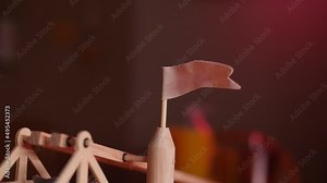 SLOW MOTION: Close up of a cloth flag on a toy wooden trebuchet as the arm is pulled down, ready to be fired.