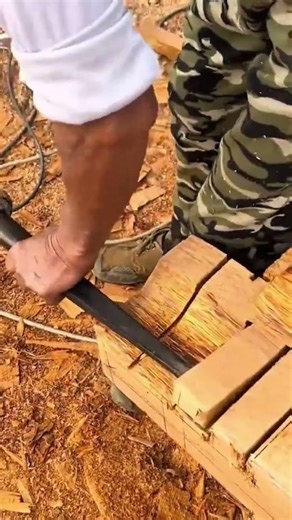 Splitting large blocks of natural wood using a heavy metal chisel tool on top of many wood shavings