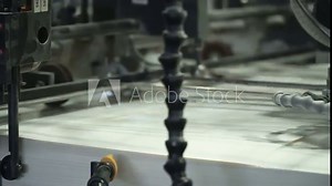 Vacuum sheet feeder supplies individual sheets of paper into printing press from the pile of paper. Related to machinery, technology of printing. Extreme closeup