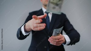 Formally dressed man carelessly throws US Dollar bills towards the camera