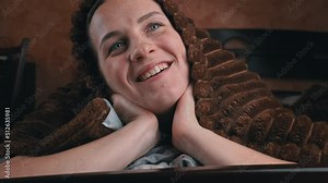 Girl lying on bed watches TV and switches channels with remote control close-up. The face of a beautiful girl looks breathtakingly at the screen with a remote control in her hands under a blanket.