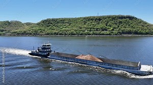 Located along the Mississippi River between Minnesota and Wisconsin's Driftless area, a towboat moves a barge filled with sand north.