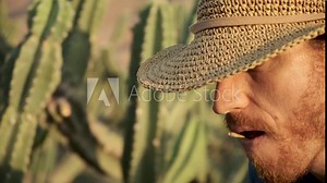 Tough cowboy Man in straw hat standing in a cactus field in the desert. Guy chewing straw in the wild wild west. cacti forest Desert Golan heights Israel. Kubo. lonely wolf guy outcast.
