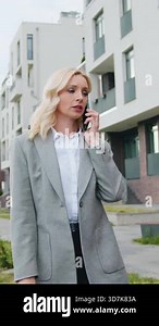 Successful caucasian middle-aged business woman talking on cellphone, approached car opens rear door of car and get sitting, lady uses of taxi service automobile. Slow motion