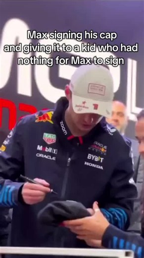 Max Verstappen signs his cap and gives it to a kid