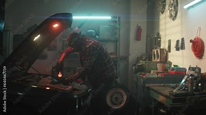 Car service, repair, maintenance concept. Auto mechanic working in township workshop, looking at open car engine, checking vehicle breakdowns. African american man with wrench working at garage.