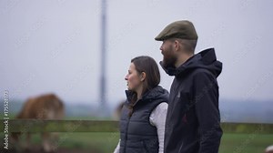 Farming couple walking in the field & checking on the livestock