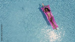 Woman with Both Hands Held High While on an Inflatable Freely Floating in Pool