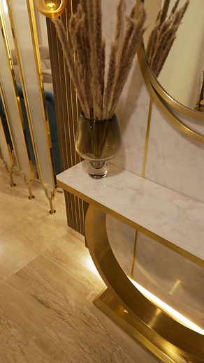 Can a foyer be grand and serene at the same time? This foyer unfolds like a welcoming embrace in a warm, neutral palette that whispers luxury! Hints of gold shimmer delicately – a whisper in the metal base of the sculptural console table, a glint in the hand-blown glass pendant lights that cascade like frozen raindrops. A discreet yet impactful divider with textured bronze and fluted glass, separates the public space from the entrance passage, offering a tantalizing glimpse beyond while maintain