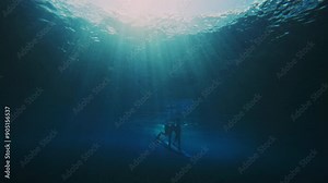 Surfer pushes board underwater to escape powerful vortex and getting caught over the falls of wave, silhouette