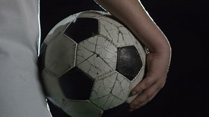 Camera focuses soccer ball held by boy illuminated by a spotlight at night Free Stock Video Footage