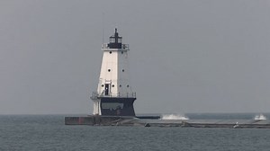 Le phare de Ludington sur le lac Michigan. Grande photo du rivage du phare. On peut voir de fortes vagues se briser. Frappé par un jour très nuageux alors que la fumée des feux de forêt canadiens s'installait.