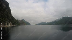 A time lapse footage of a lake created by dam with an overcast sky and mountains. 4k 3840x2160, wide and lockdown shot.