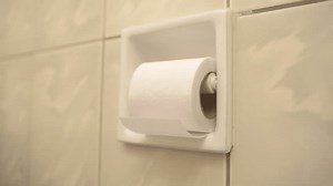 woman unrolling toilet paper. close-up of a toilet paper being unrolled by a woman's hand