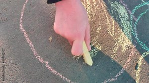 A child draws on the asphalt with colored chalk. Drawing on the road.
