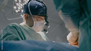 Close up surgeon man in protective mask physician doctor medic team operate patient laparoscopy surgical operation microscope surgery with medical tools in operating room hospital clinic health care