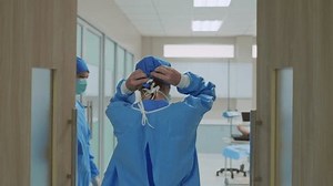 clip-3401654389-professional-doctors-tying-surgical-cap-while-walk