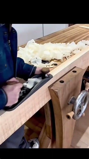 Woodworker using hand plane smoothing long wooden board edge