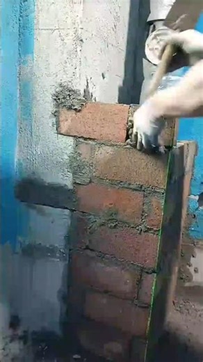 carefully building a tall narrow brick column using a metal trowel and mortar #shorts