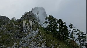 fly close and low over mountain ridge with sharp rocks, clouds floats over the peak. aerial view