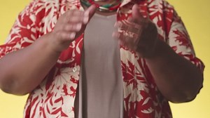 Midsection of unrecognizable plus size Black woman in Hawaiian print shirt clapping with her hands while dancing on bright yellow studio background
