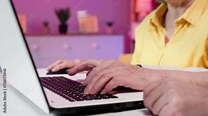 old man and elderly woman having fun playing games on laptop and pressing keys on keyboard while sitting at a table in room, hands close-up