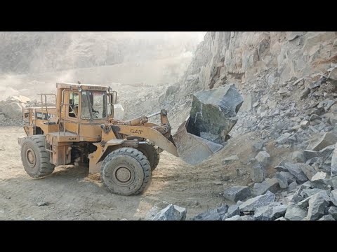 Heavy machine rocks loading in action: caterpillar loader 966E big rocks loading damper and trolleys