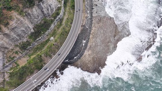 Winter view of a sea cliff bridge over the ocean with falling snowflakes, creating a calm holiday background. Perfect for New Year 2026 projects, Christmas visuals, seasonal advertising, and cinematic