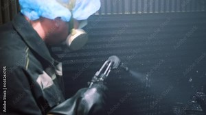 A man in a factory sprays polyurethane on a part. Spraying polyurethane on metal to protect against corrosion and abrasion. Coating with two-component cold curing polyurethanes for industrial products