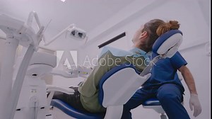 A male patient sitting in a dental chair reclining, waiting for a dental examination in a well-equipped dentist's office with modern equipment