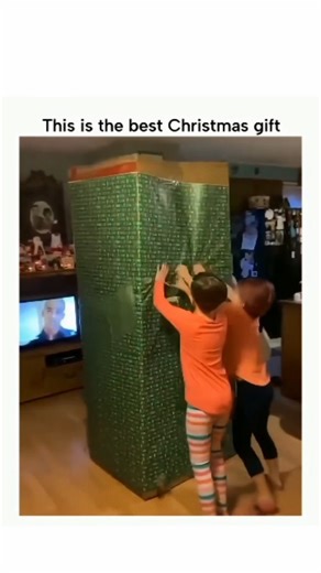 Dark | Raw | Weird on Instagram: "The post features a 27-second clip centered on an oversized Christmas gift being unboxed with exaggerated effort, as multiple people struggle to tear through layers of wrapping, tape, and packaging. The sheer scale of the box turns the unboxing into a physical task rather than a simple reveal, building suspense as viewers wait to see what could possibly justify the size. As the wrapping comes off piece by piece, reactions shift between excitement and disbelief,