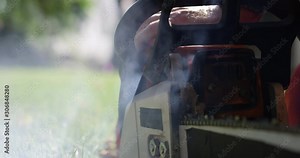 Pull starting chainsaw as smoke comes out of 2 stroke gas engine - close up