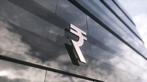 Indian rupee symbol currency sign on a modern glass skyscraper. Mirrored sky and city on modern facade. Business and finance concept