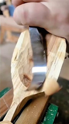 Hand carving a wooden spoon bowl using a sharp hook knife producing thin wood shavings