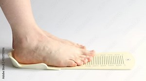 A woman's foot is measured on a measuring board to determine the shoe size, measuring the foot size