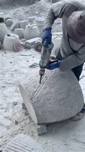 A worker is drilling large stone block for shaping