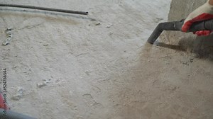 The builder vacuums the concrete floor for further pouring. A worker vacuums a concrete floor. Construction services for cleaning the sleeve with an anchor bolt.