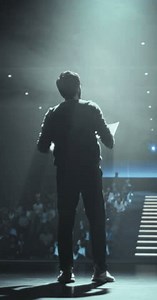 Vertical Screen: Thought Leader Standing Under a Spotlight, Making an Inspiring Presentation About Sustainable Innovations at Technology Conference. Indian Man Talking to an Audience in a Dark Venue