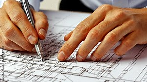 Architect drafting detailed blueprints: focused hand movement on technical drawings