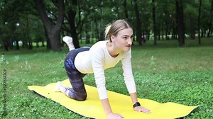 a girl outdoors in the park goes in for sports in a sports leggings on a yellow sports mat in the background a meadow and trees