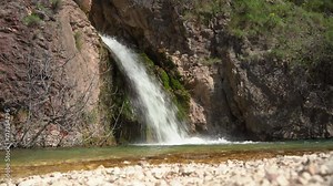 Waterfall stream with white foam flows with pressure from a cliff cliff over stones overgrown with moss into a mountain river Picturesque relaxing natural landscape reserve, source of clean water