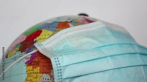 Earth globe wears a medical mask. A medical mask is worn on an earth globe. World quarantine, coronavirus pandemic. World quarantine symbol.