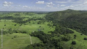 Drone flies to the right across lush green valley with blue sky and clouds painting an image that resembles a computer screensaver