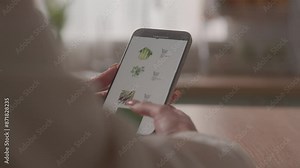 Back view unrecognizable girl woman female client buyer choose vegetables online using website internet supermarket order food delivery buy shopping products at kitchen mobile phone smartphone screen