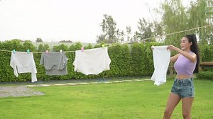 Young asian woman hanging laundry on washing line for drying